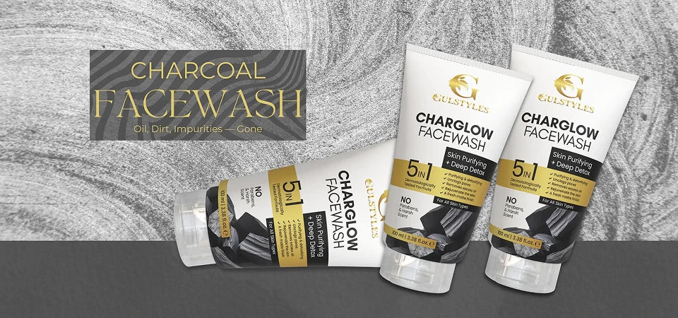 Three tubes of Existiles Charcoal Facewash displayed on a dark gray surface against a textured gray background, with one tube lying down and two standing upright.